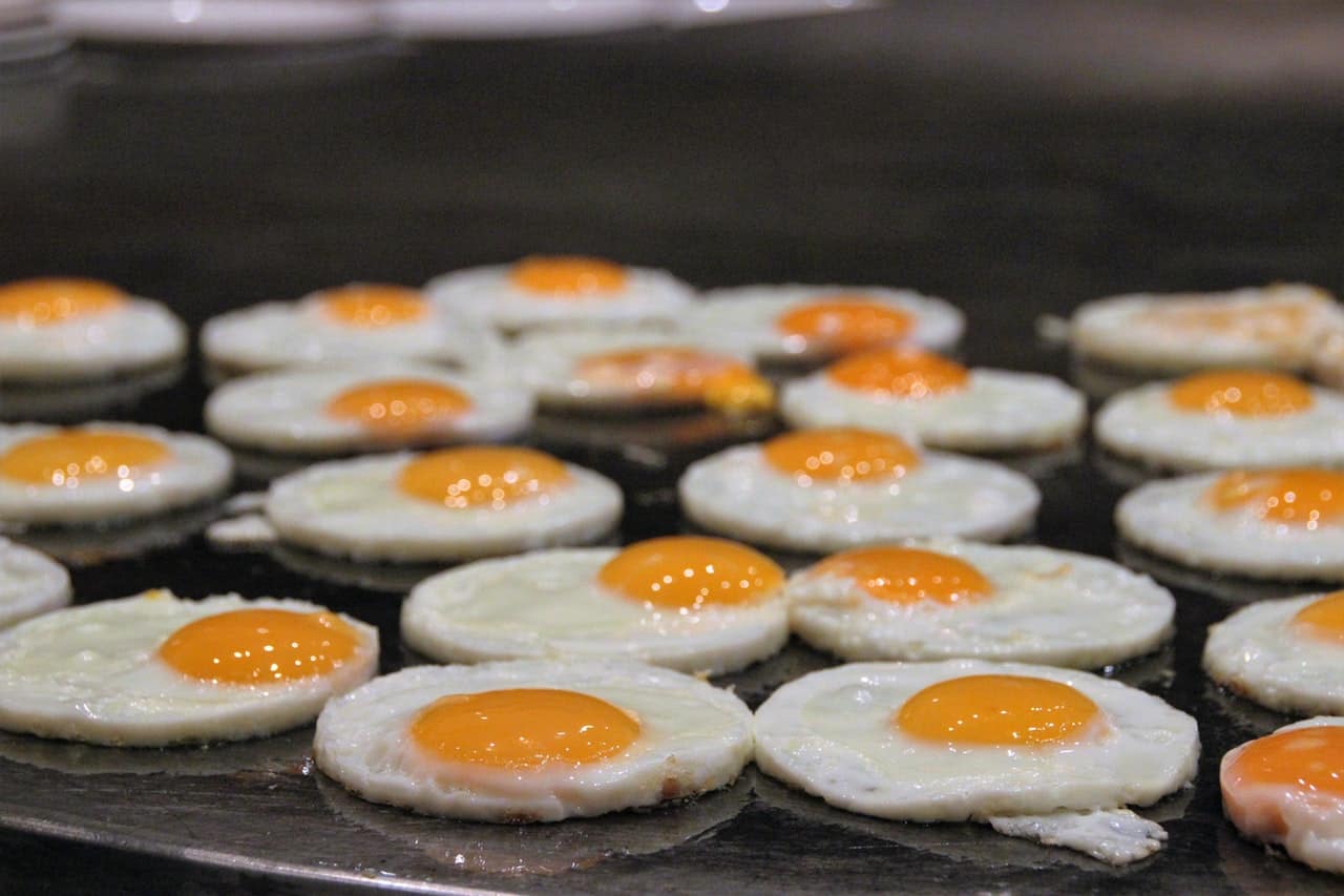 Several sunny side up eggs cooking